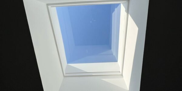 A square skylight set in a dark ceiling lets sunlight and blue sky shine through, casting bright shadows on the white frame—perfect inspiration for water damage restoration Toronto projects seeking bright, refreshed spaces.