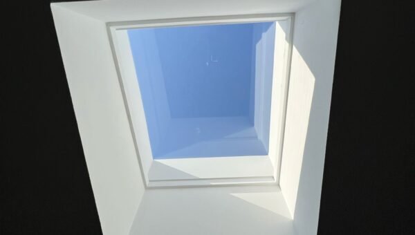 A square skylight set in a dark ceiling lets sunlight and blue sky shine through, casting bright shadows on the white frame—perfect inspiration for water damage restoration Toronto projects seeking bright, refreshed spaces.